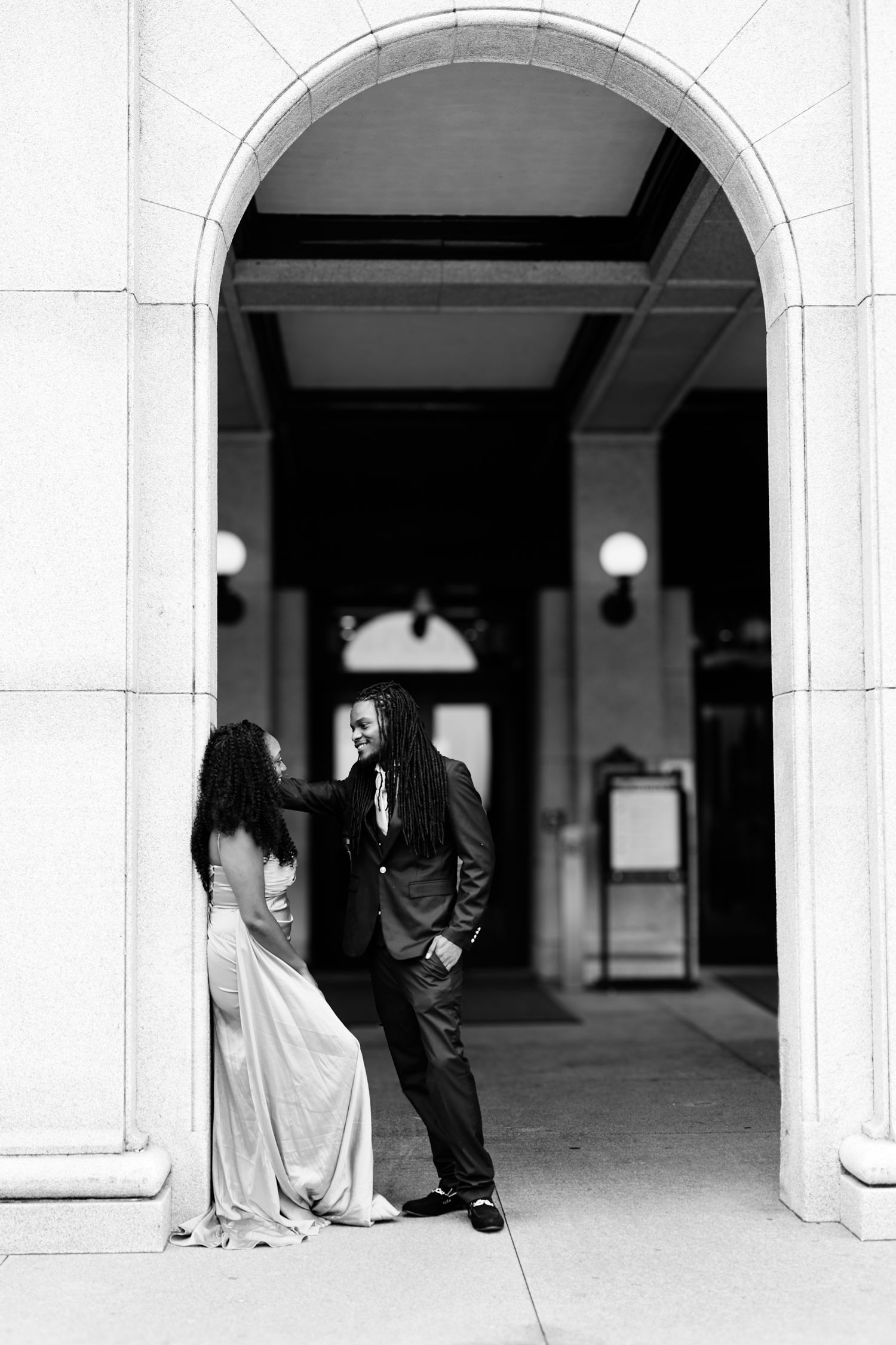A romantic black and white photo of a couple sharing an intimate moment under an arched passageway.