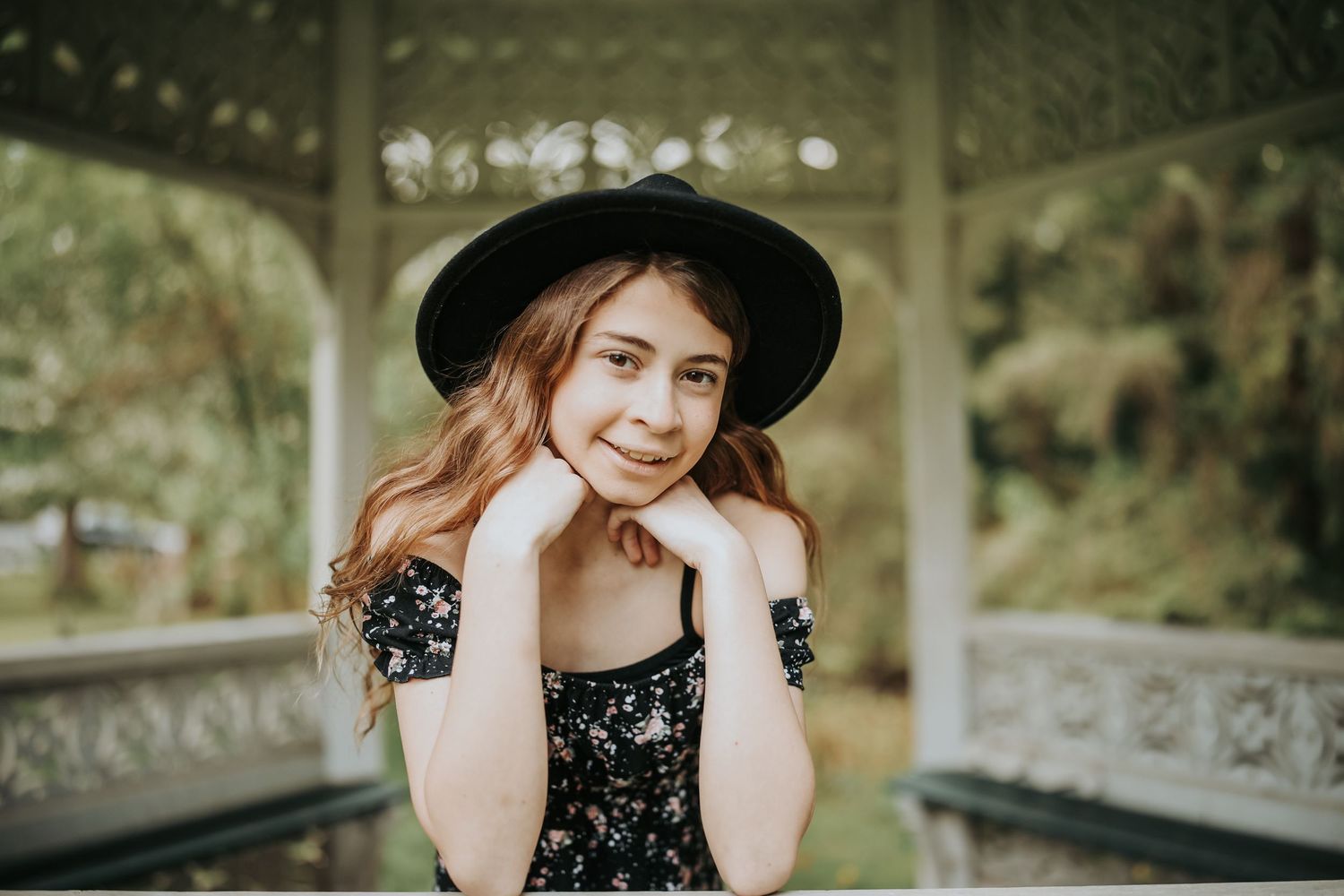 A series of outdoor portrait photos showing someone in a black dress and hat posing in a garden setting.