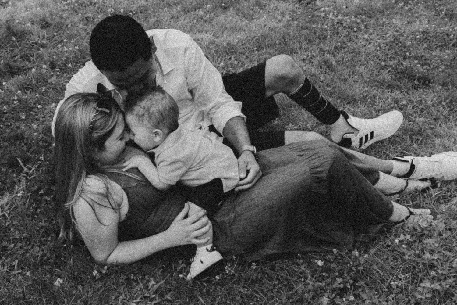 A romantic sequence of black and white photos shows a couple lying in grass sharing tender moments together.