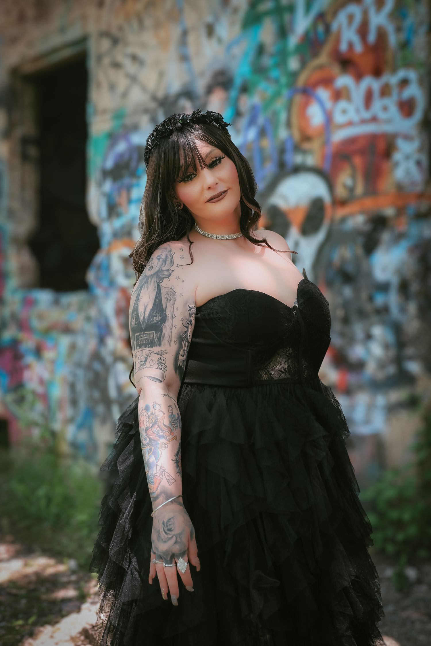 A person in a black tulle dress poses against a graffiti wall in an artistic photoshoot series.