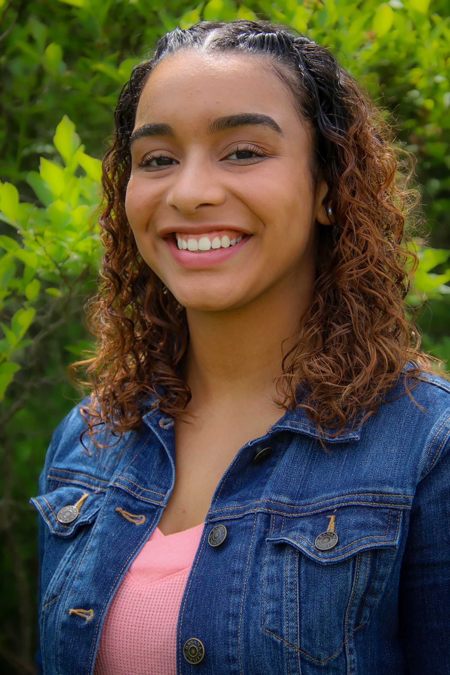 A series of outdoor portraits showing someone wearing a denim jacket and pink top against a green leafy background.