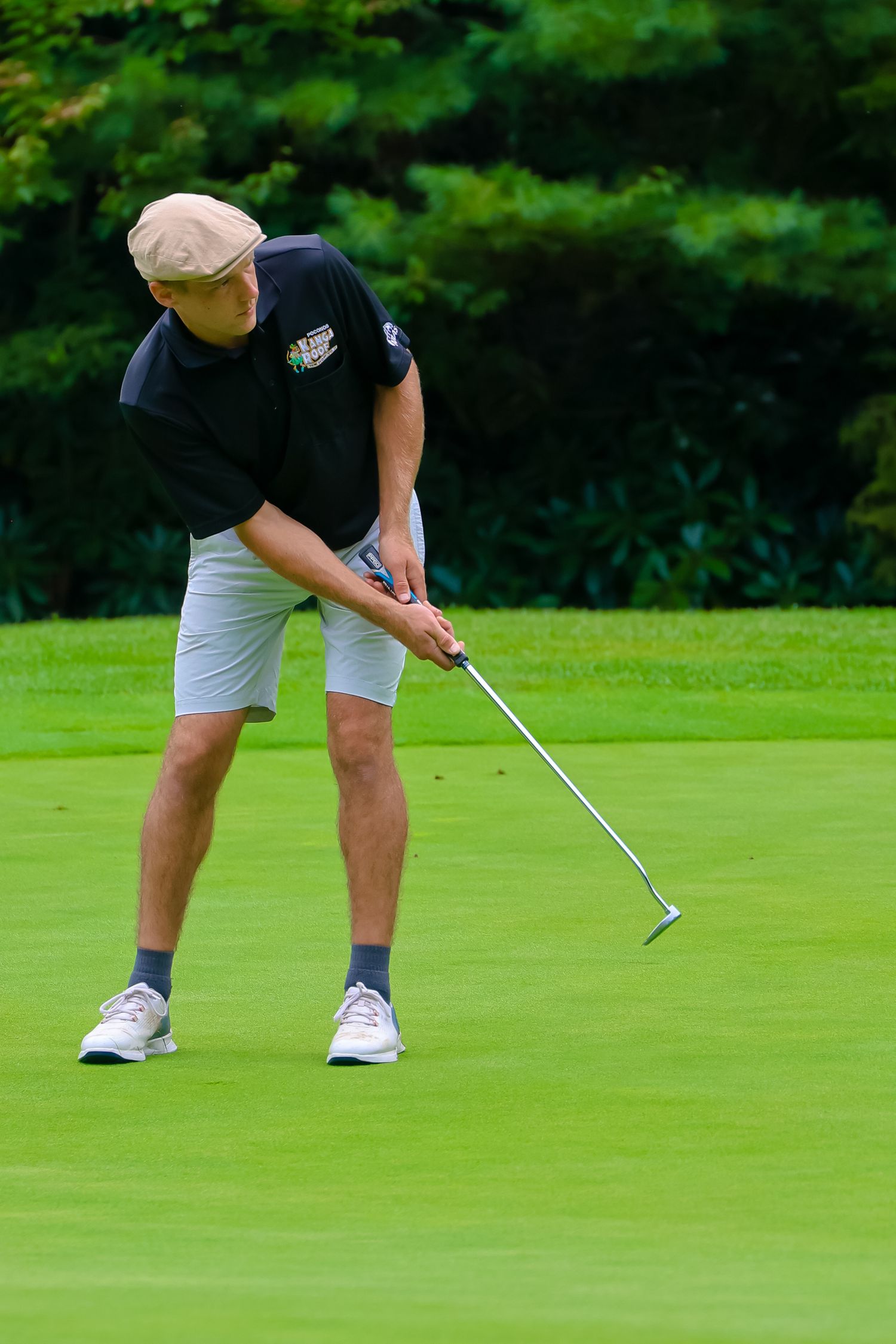 A golfer on a green putting course lines up their shot with careful precision and focus.