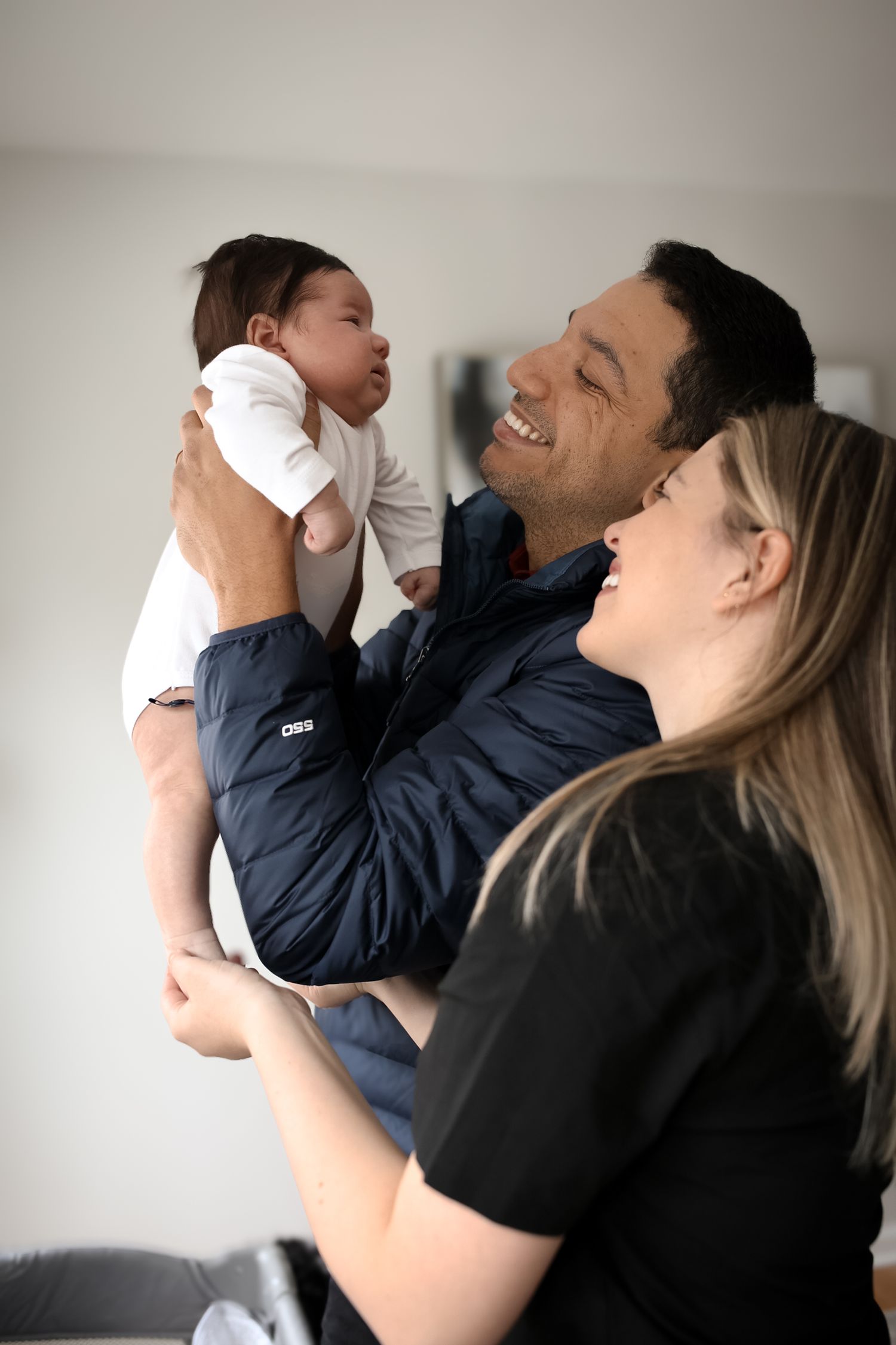 A series of candid photos showing a parent lifting and playing with a baby in a white room.