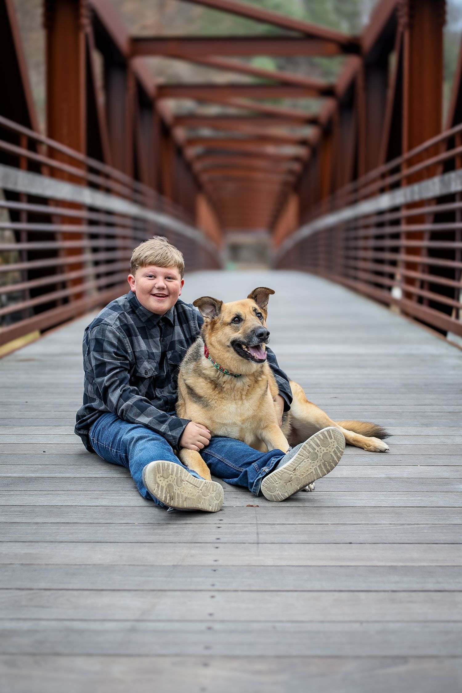 A person and German Shepherd mix dog pose together on a wooden bridge in a series of casual outdoor photos.