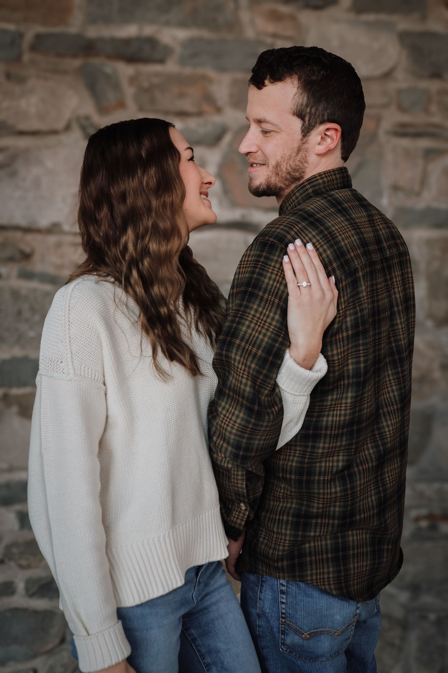 Romantic couple in casual winter attire share intimate moments against rustic stone wall in progressive photo series.