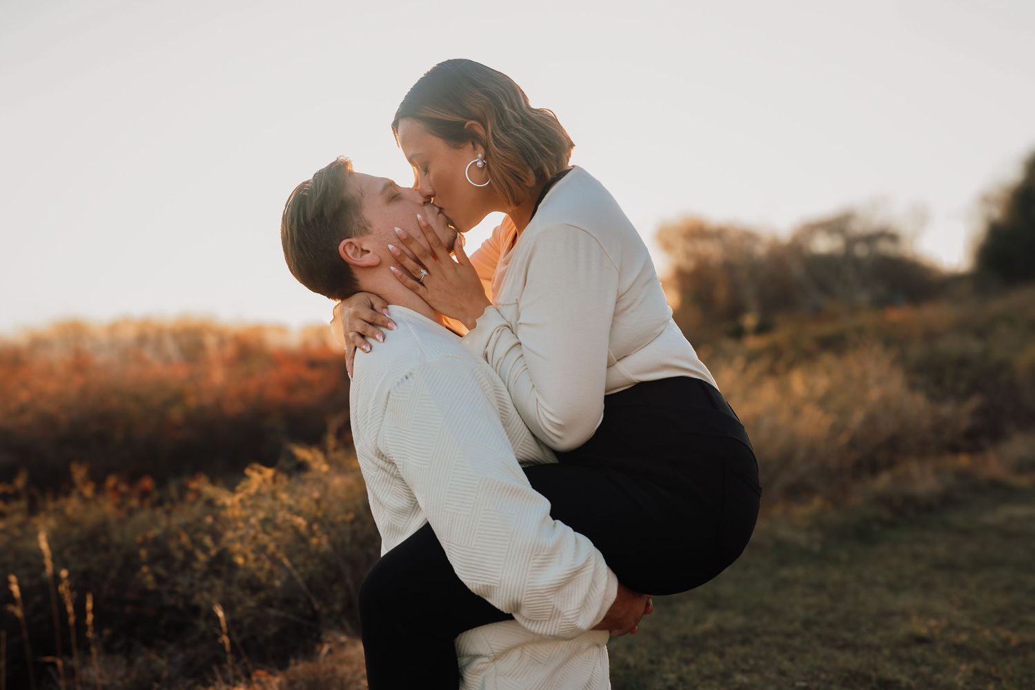 Romantic silhouettes embrace during golden hour in a natural outdoor setting.