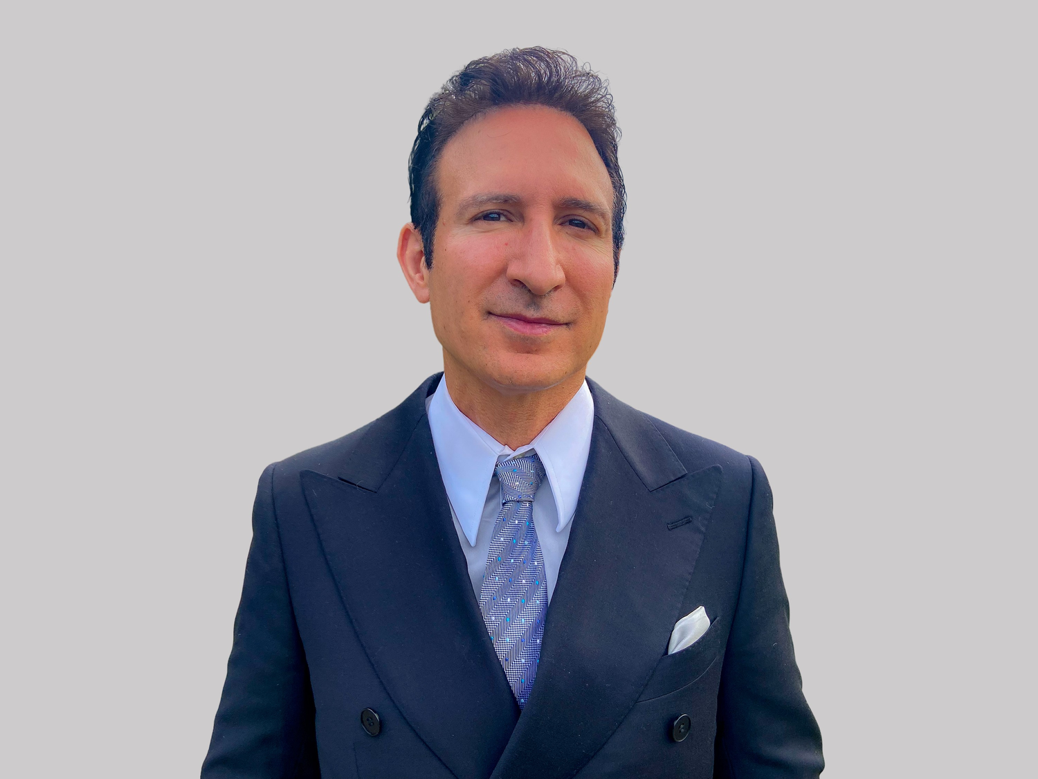 A person in a dark business suit and blue tie shown in four similar professional headshots.