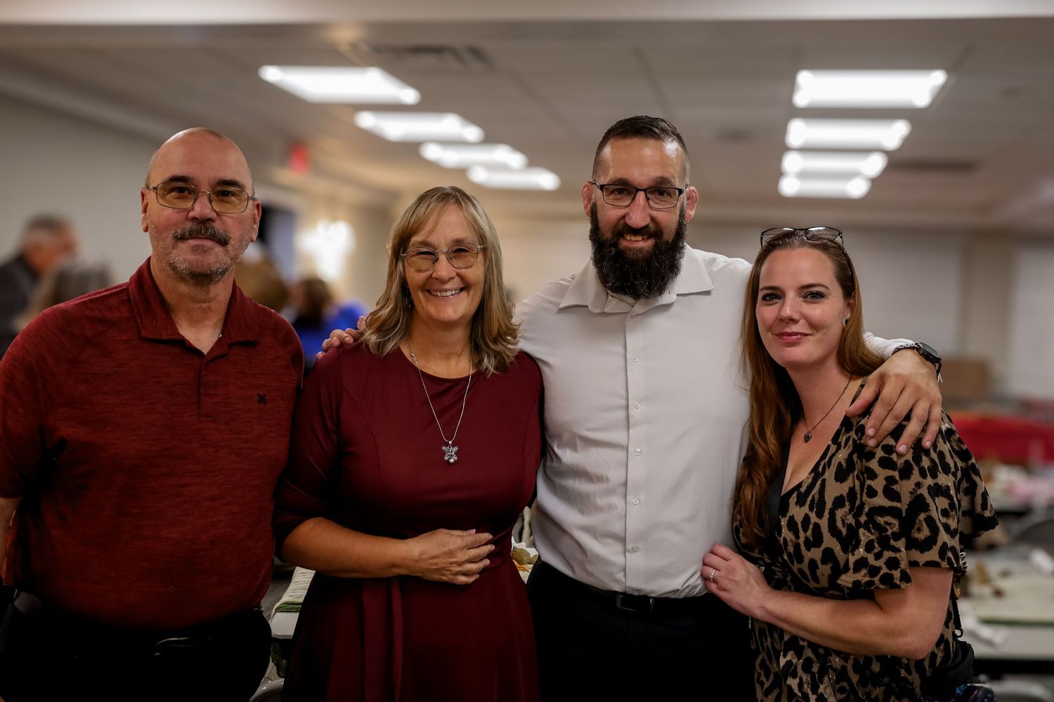 A group of colleagues stand together in an office hallway under fluorescent lighting.