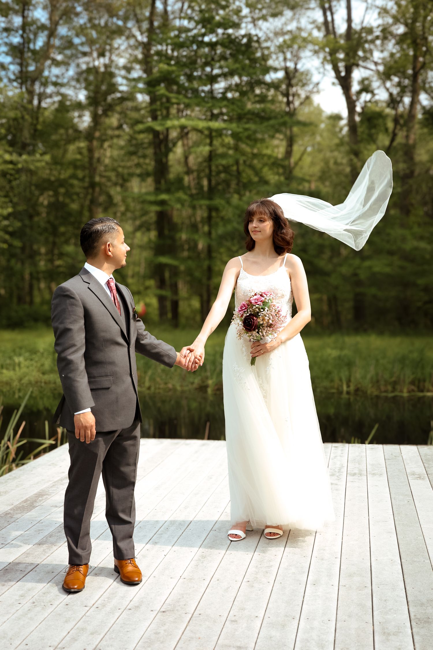 A sequence of wedding photos showing a couple on a white deck with trees in the background as the veil catches the wind.