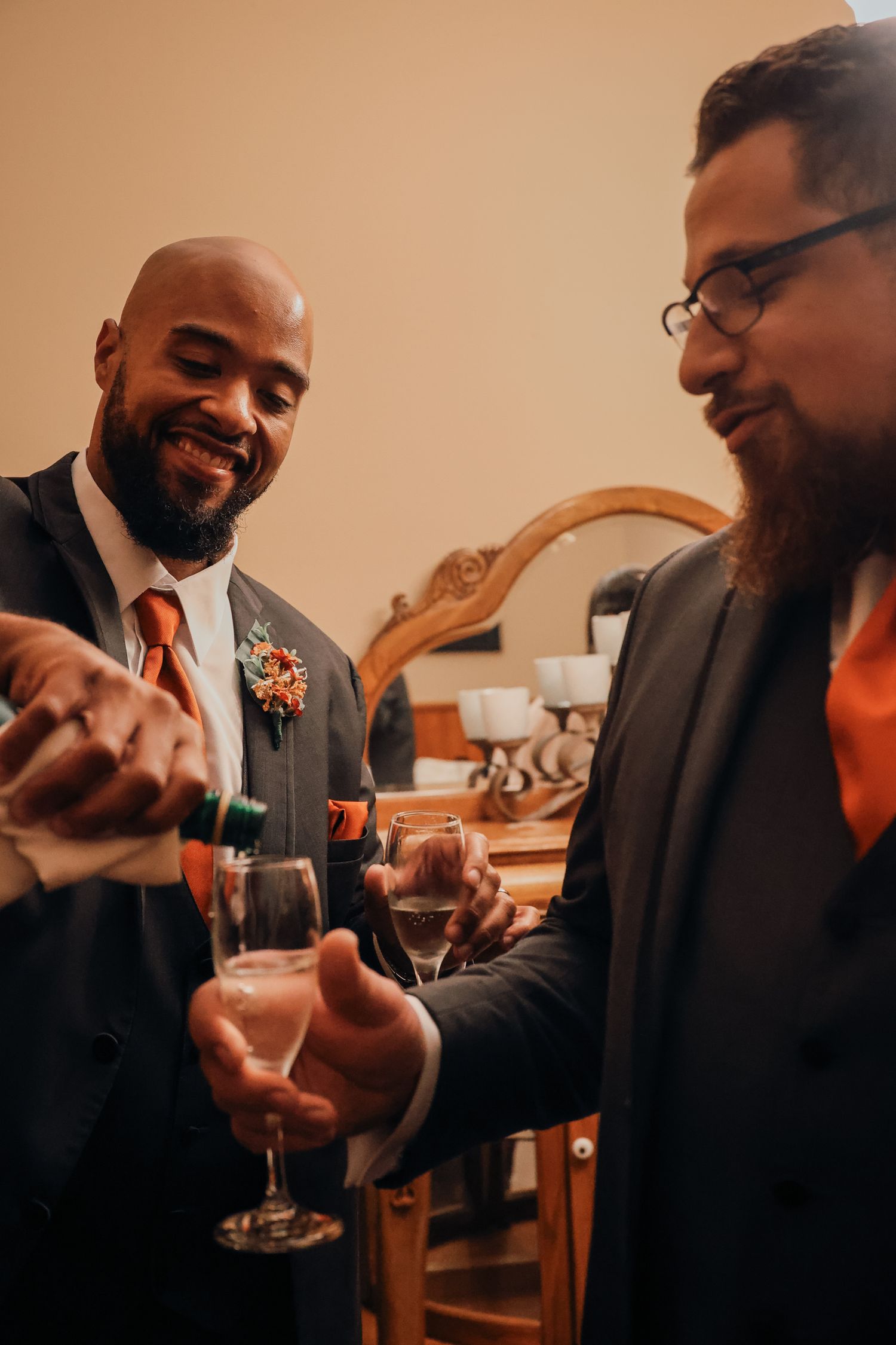 Two people in suits share a toast with wine glasses during a celebratory moment at an indoor event.