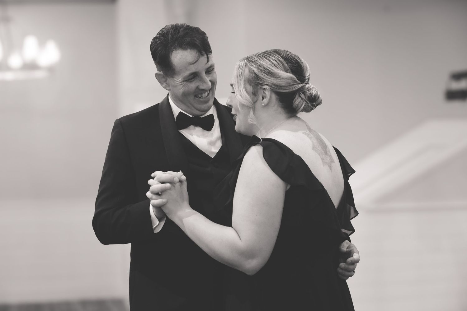 A couple performs an elegant dance move together in formal attire at a ballroom dance event.