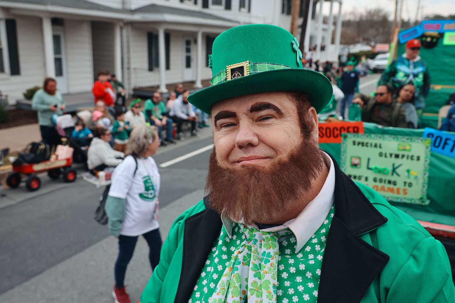 Man dressed as a leprechaun in green hat and suit at a St. Patrick's Day parade.