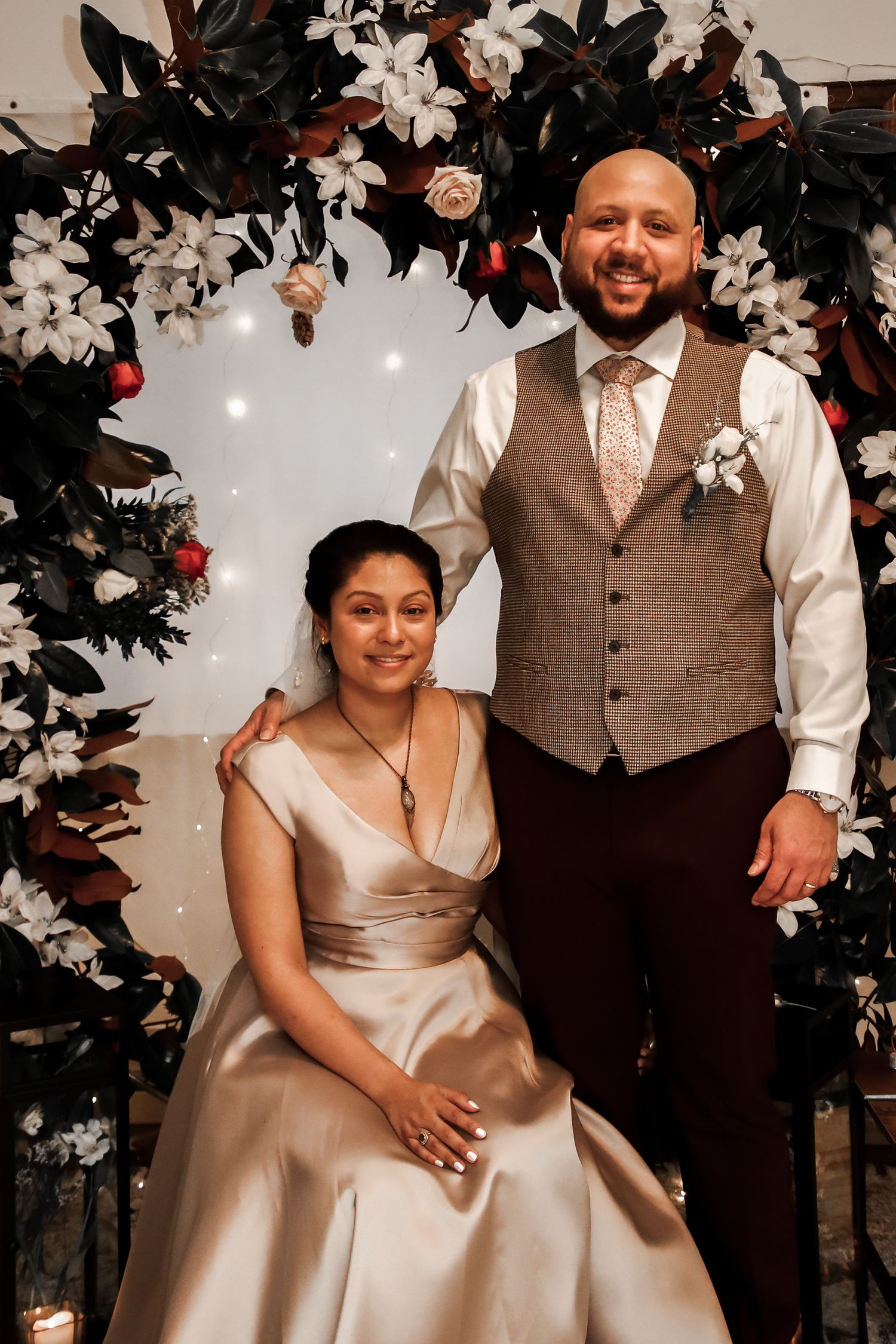 Newlyweds share intimate moments during their wedding photoshoot with floral decor and romantic lighting.