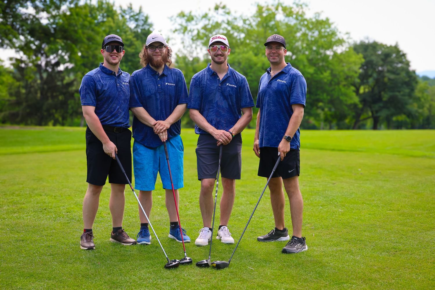 A group of golfers stand together on a lush green golf course during a sunny day.