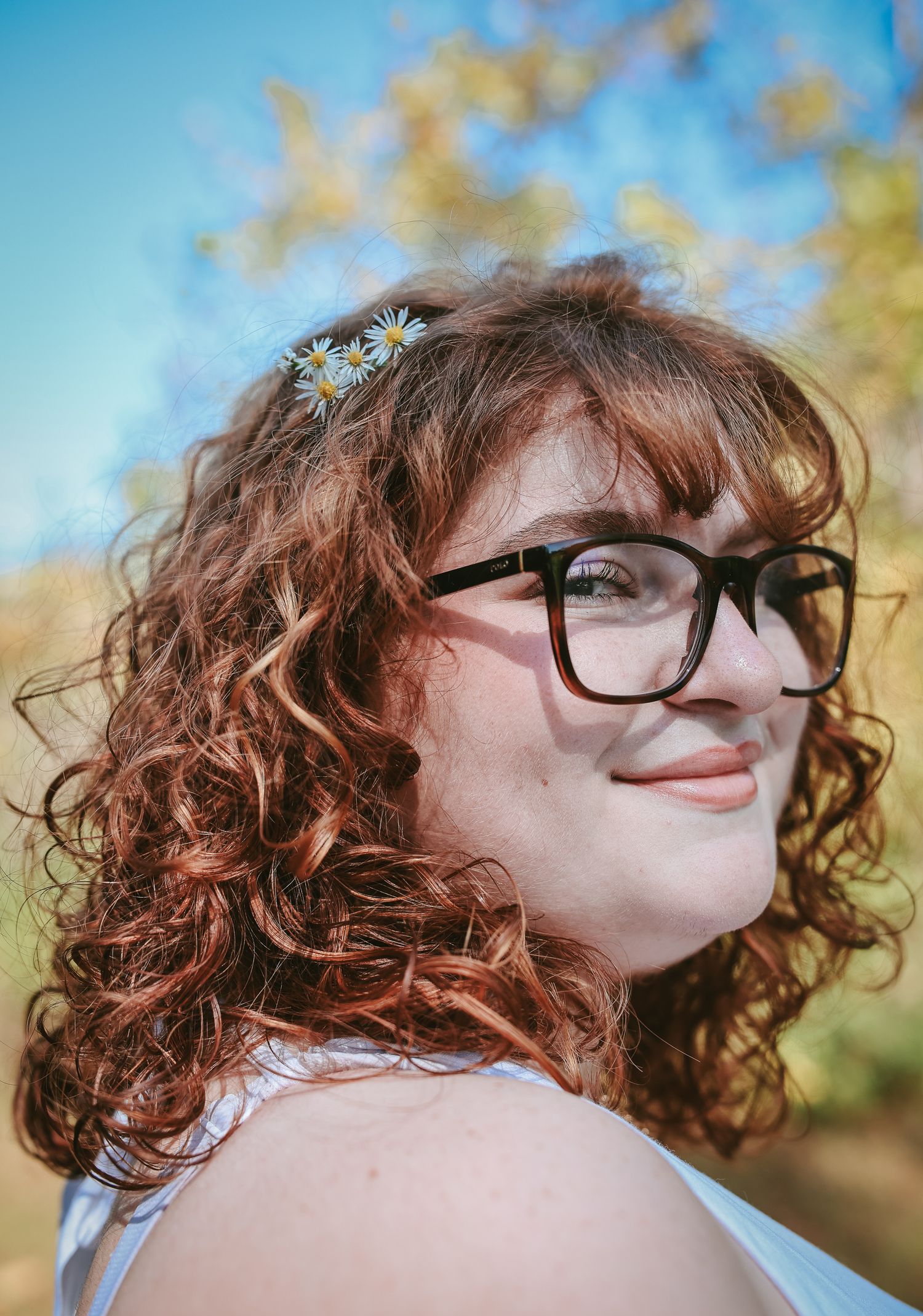 A sequence of five photos showing curly red hair and glasses against a soft blue and golden bokeh background.
