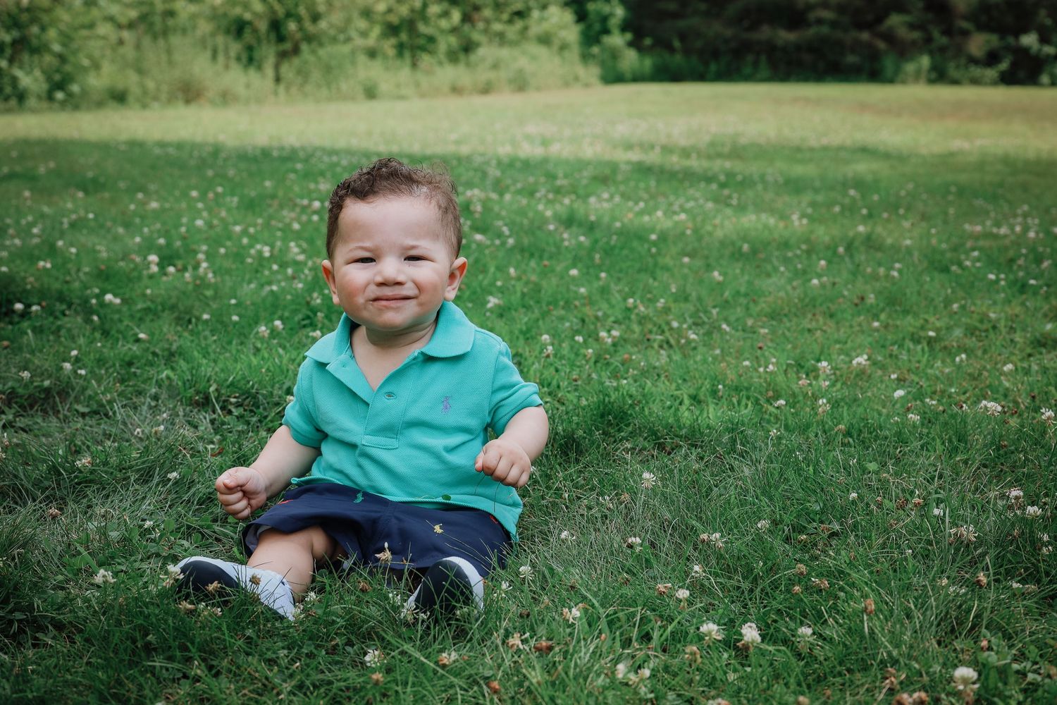 A series of outdoor photos showing someone sitting and playing on lush green grass in summer.