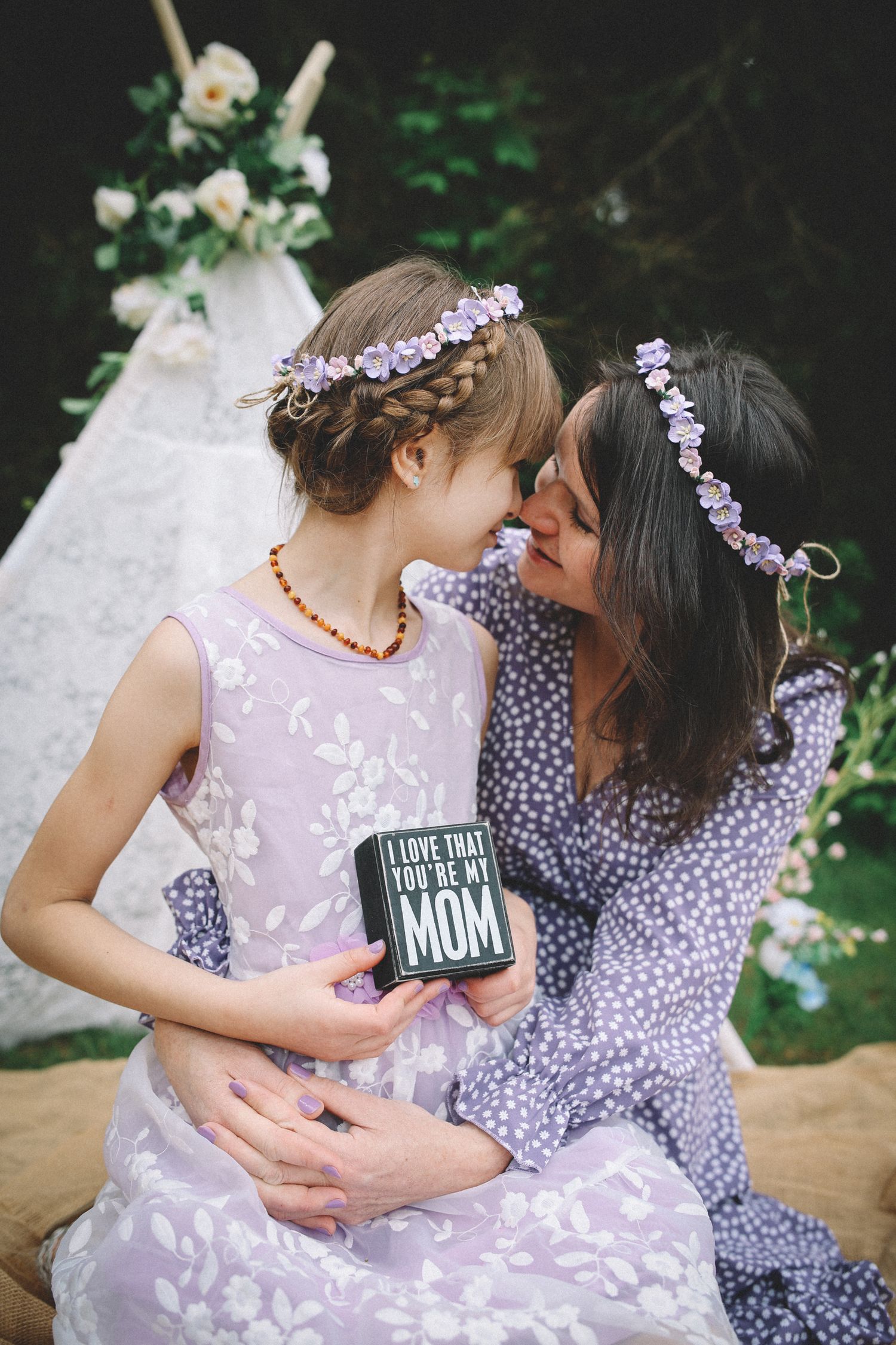 Mother and daughter in matching floral outfits share tender moments in outdoor photo sequence.