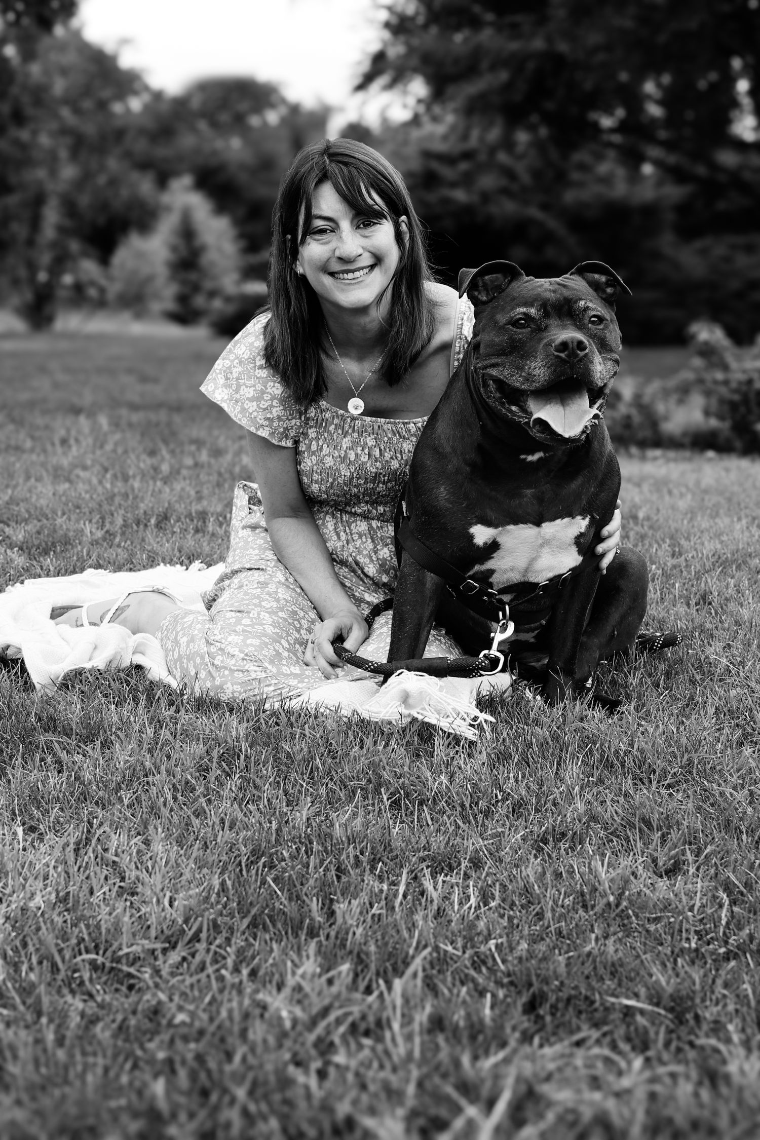 A series of black and white photos showing a person lying in grass with a small black dog on a sunny day.