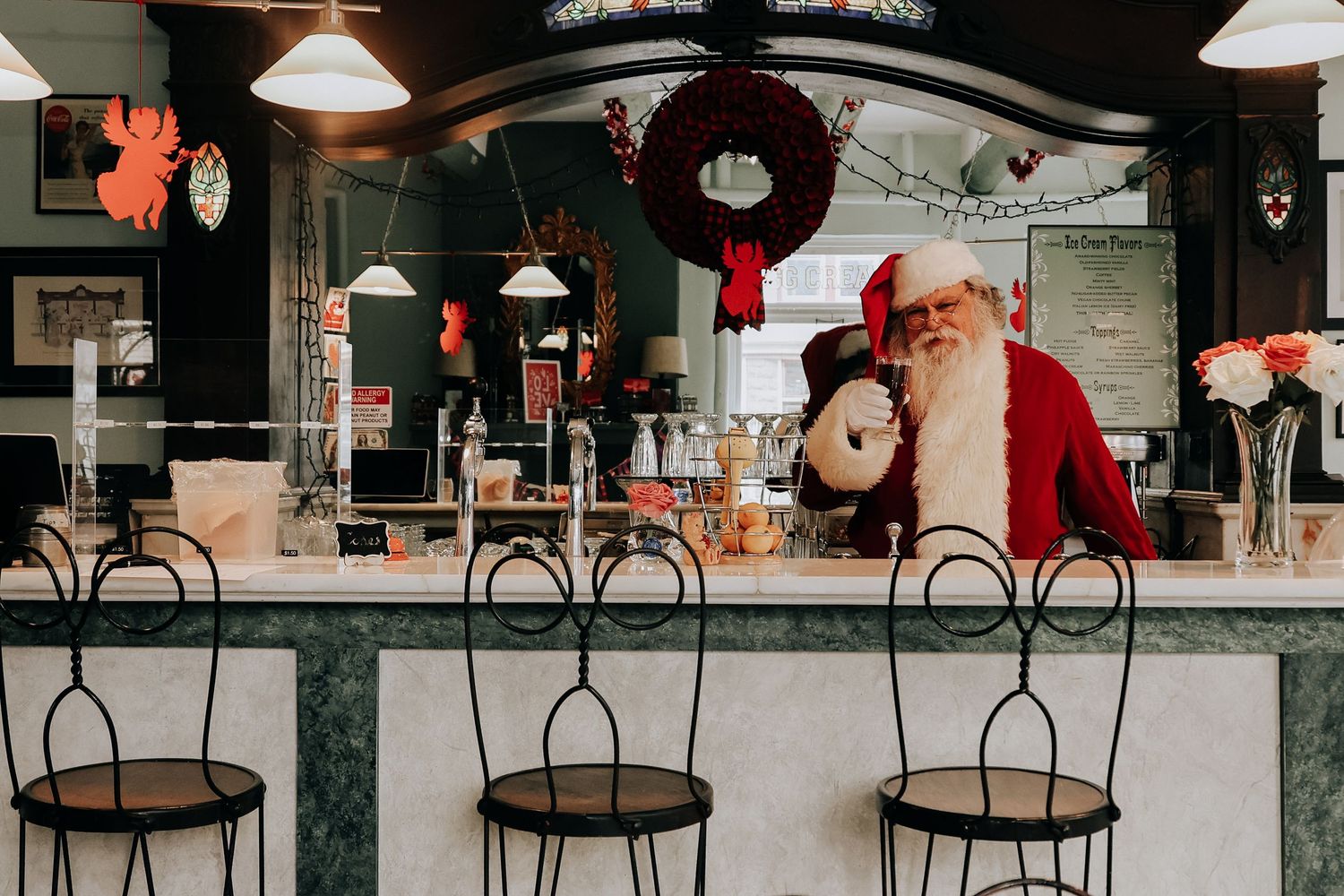 Empty bar counter with black metal stools and holiday decorations including a festive Santa Claus display.