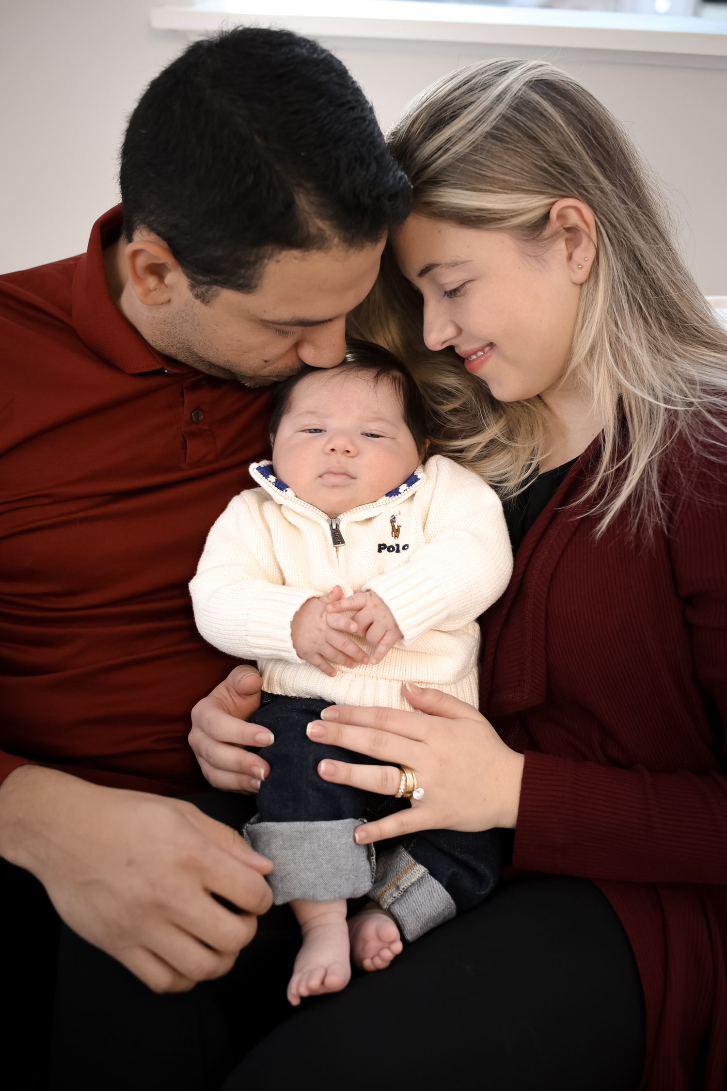 A family shares tender moments while cuddling with their sleeping baby in a series of intimate photographs.