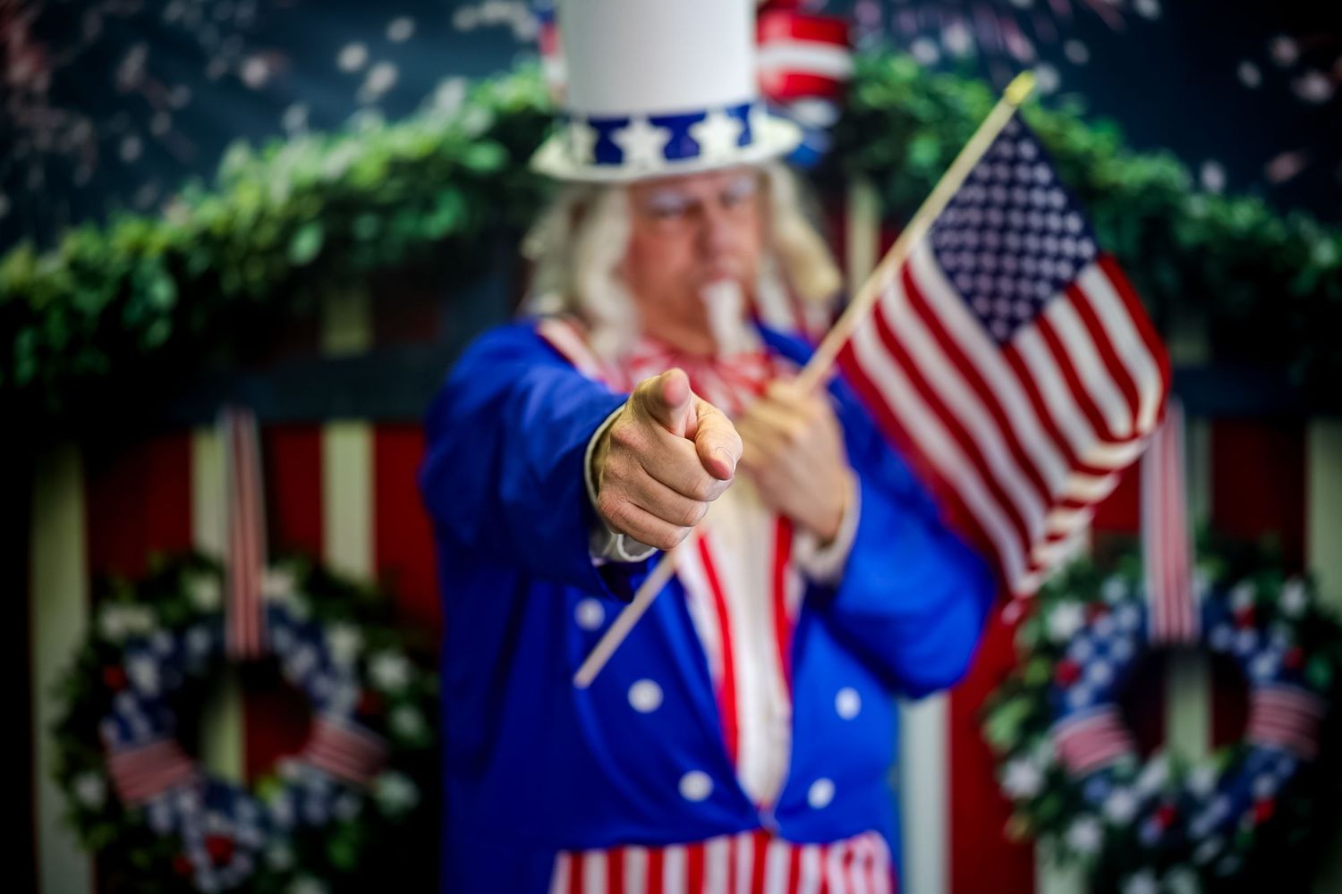 Uncle Sam costume character pointing forward while holding American flags, perfect for 4th of July celebrations.