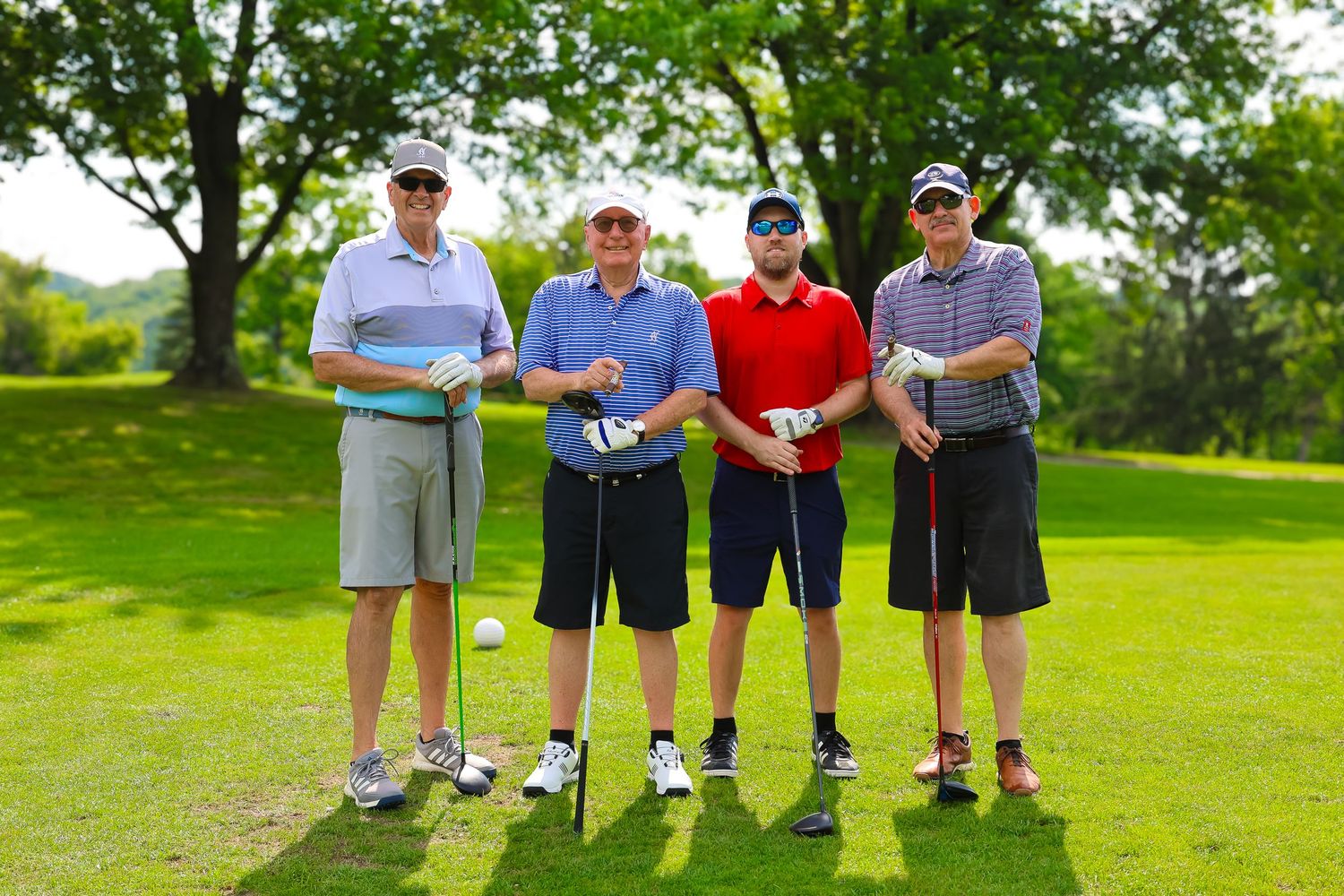 Four golfers stand together on a lush green golf course fairway.