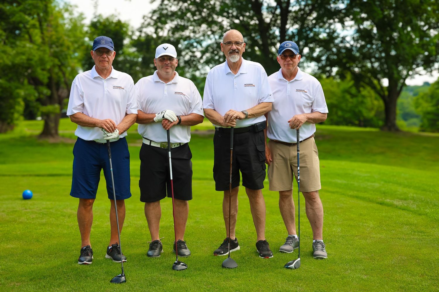 Golfers posing together on a lush green golf course during a summer day.
