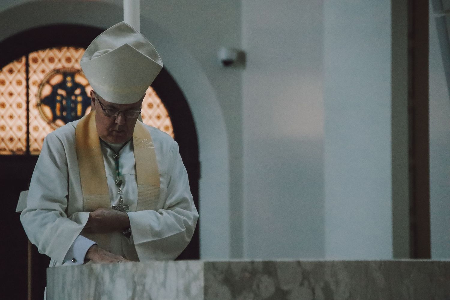 A person in traditional Islamic attire bows their head in prayer at a mosque.
