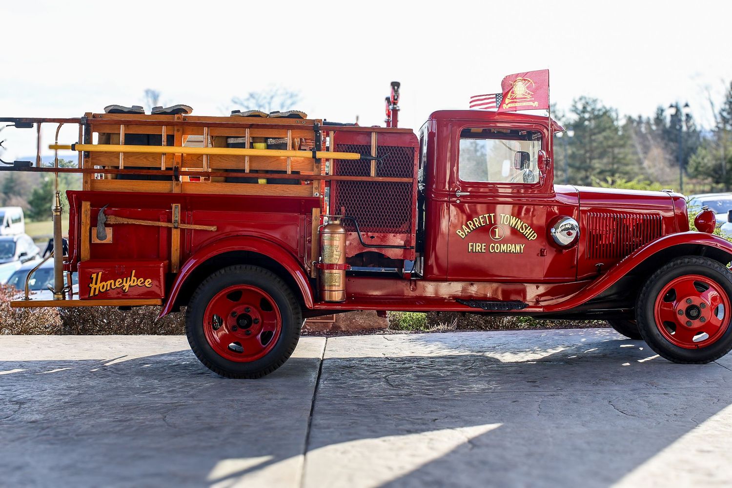 Vintage red fire truck with wooden ladder and antique equipment displayed at an outdoor event.