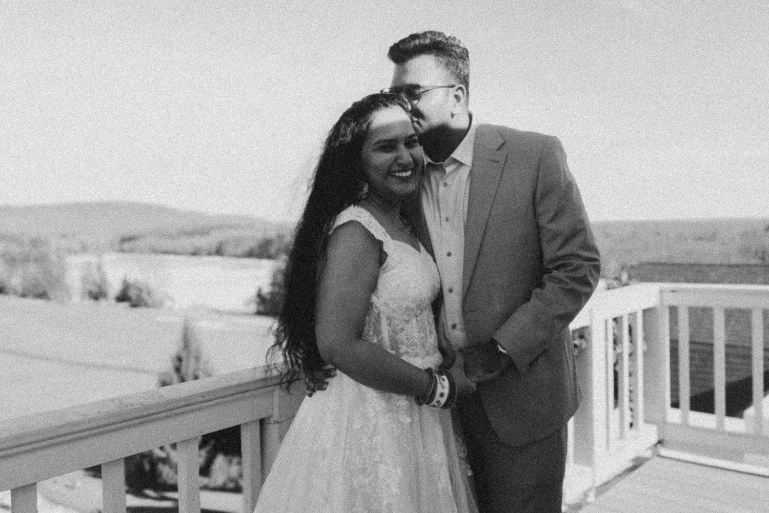 A series of black and white wedding photos showing romantic moments between a couple outdoors and near a building.