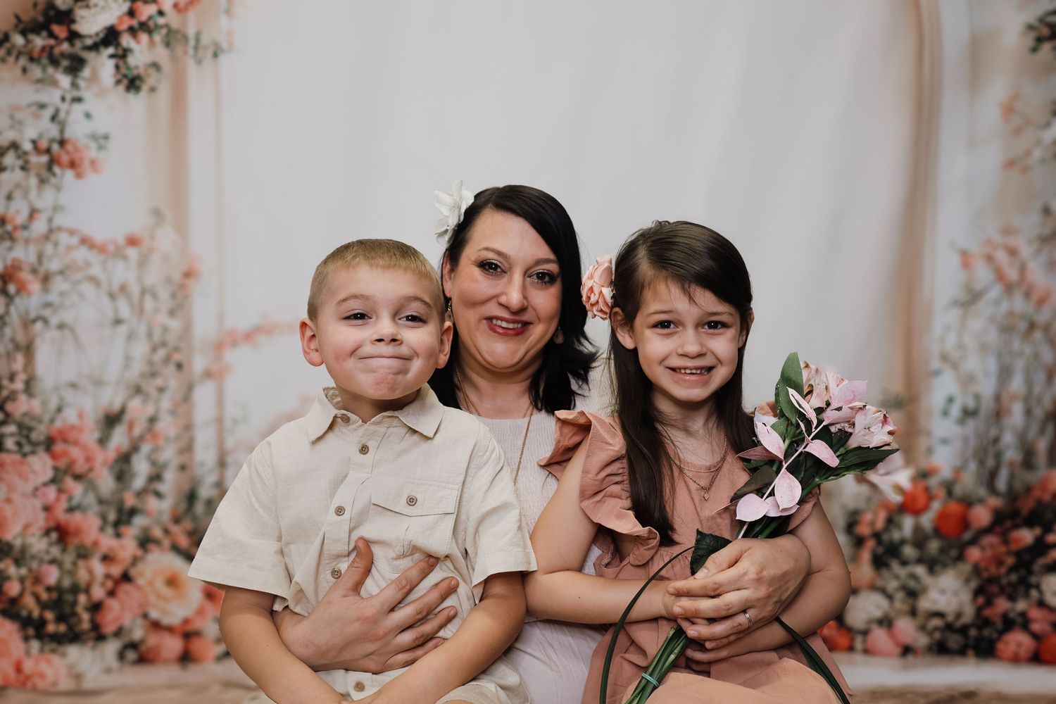 Family portrait against floral backdrop with pink decorative flowers and white curtain.