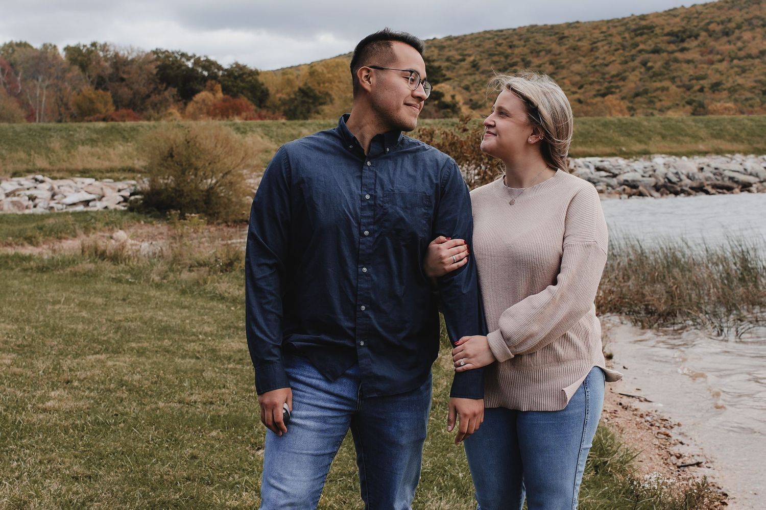 A couple walks together in nature across multiple scenic outdoor locations during autumn.
