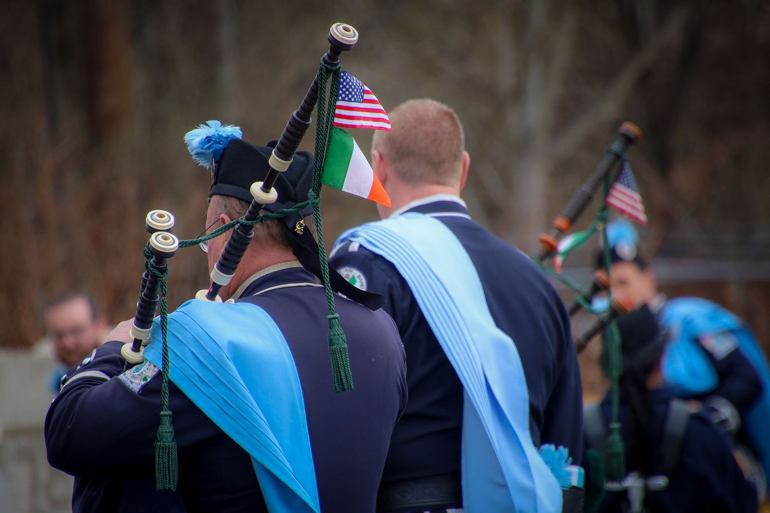 Police officers in blue vests stand in formation during an outdoor gathering with American flags visible.