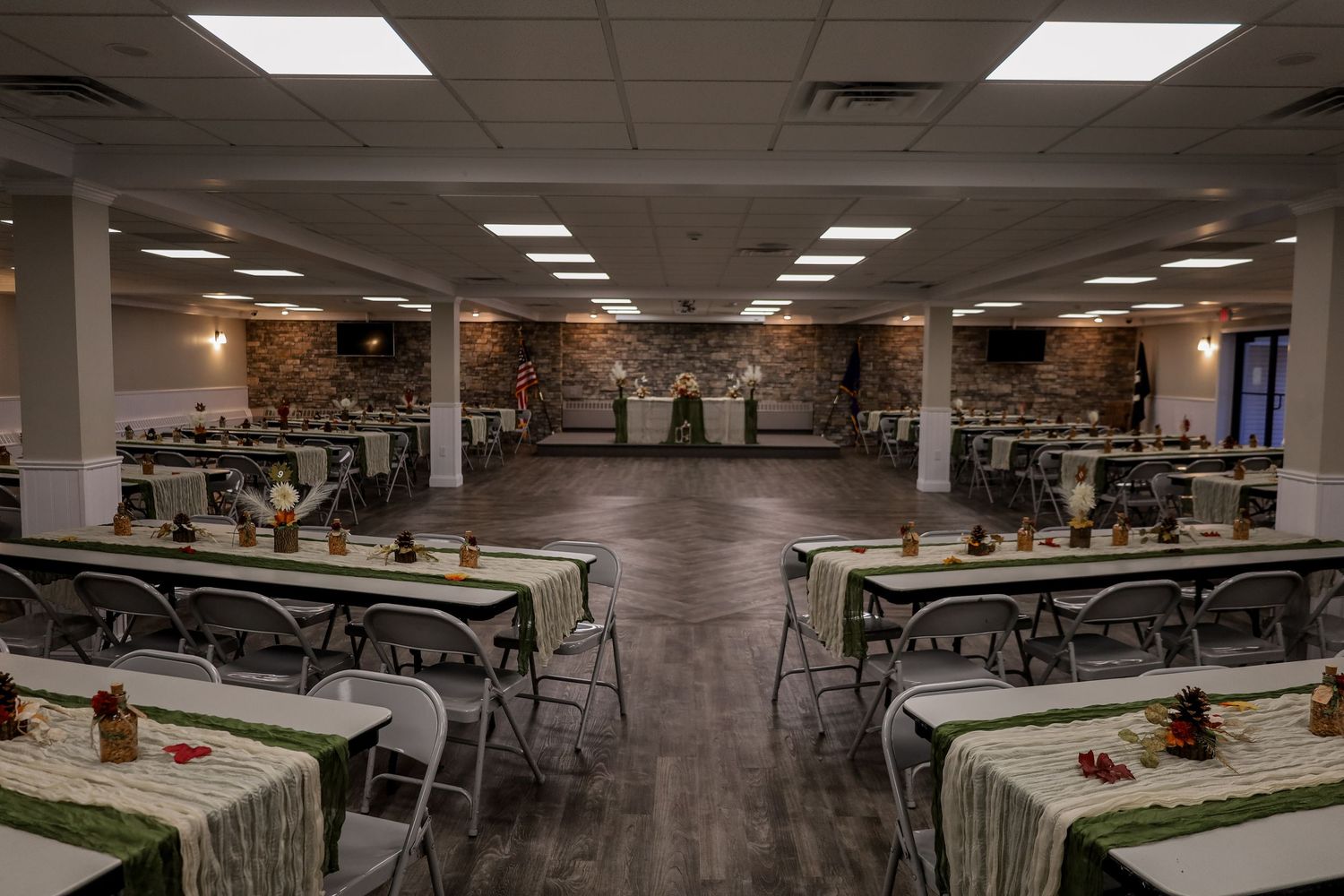 Large empty cafeteria with rows of tables and chairs under fluorescent lighting in an institutional setting.