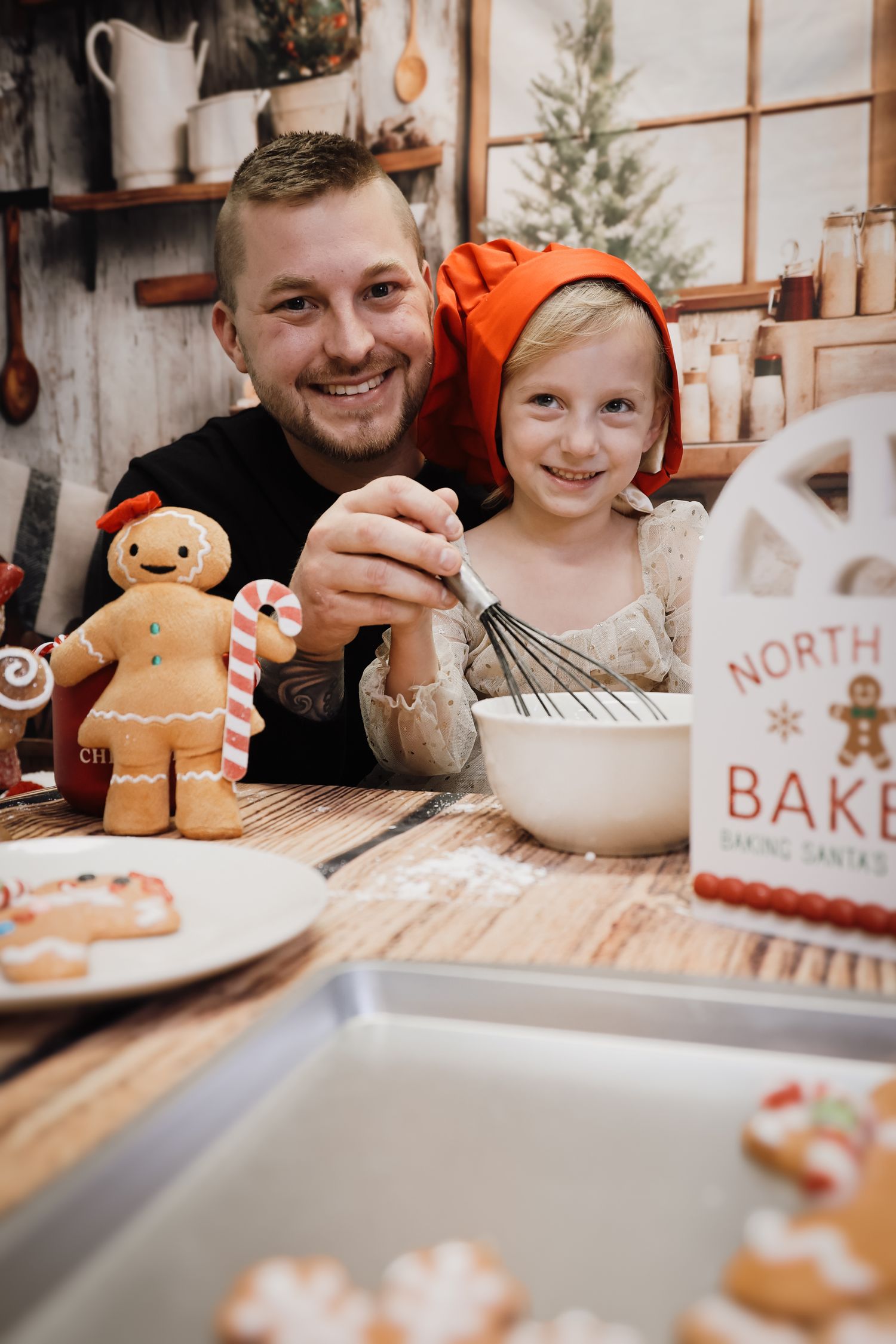 Father and daughter smile while baking Christmas gingerbread cookies together in a festive holiday kitchen.