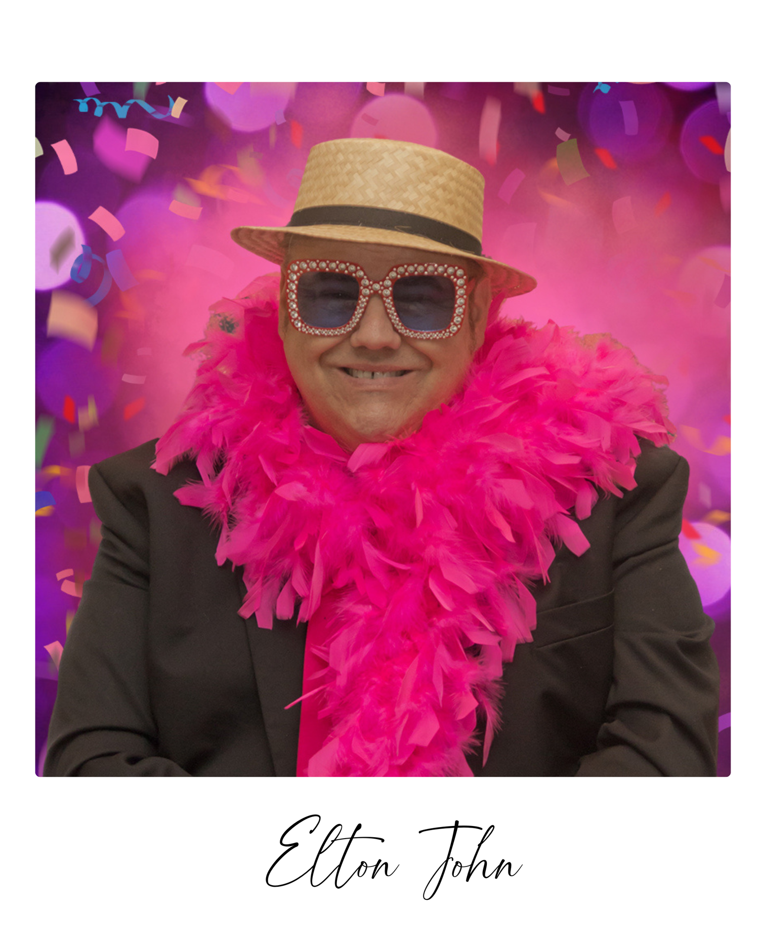 A person wearing a black suit, straw hat, and pink feather boa poses in front of a vibrant magenta backdrop.
