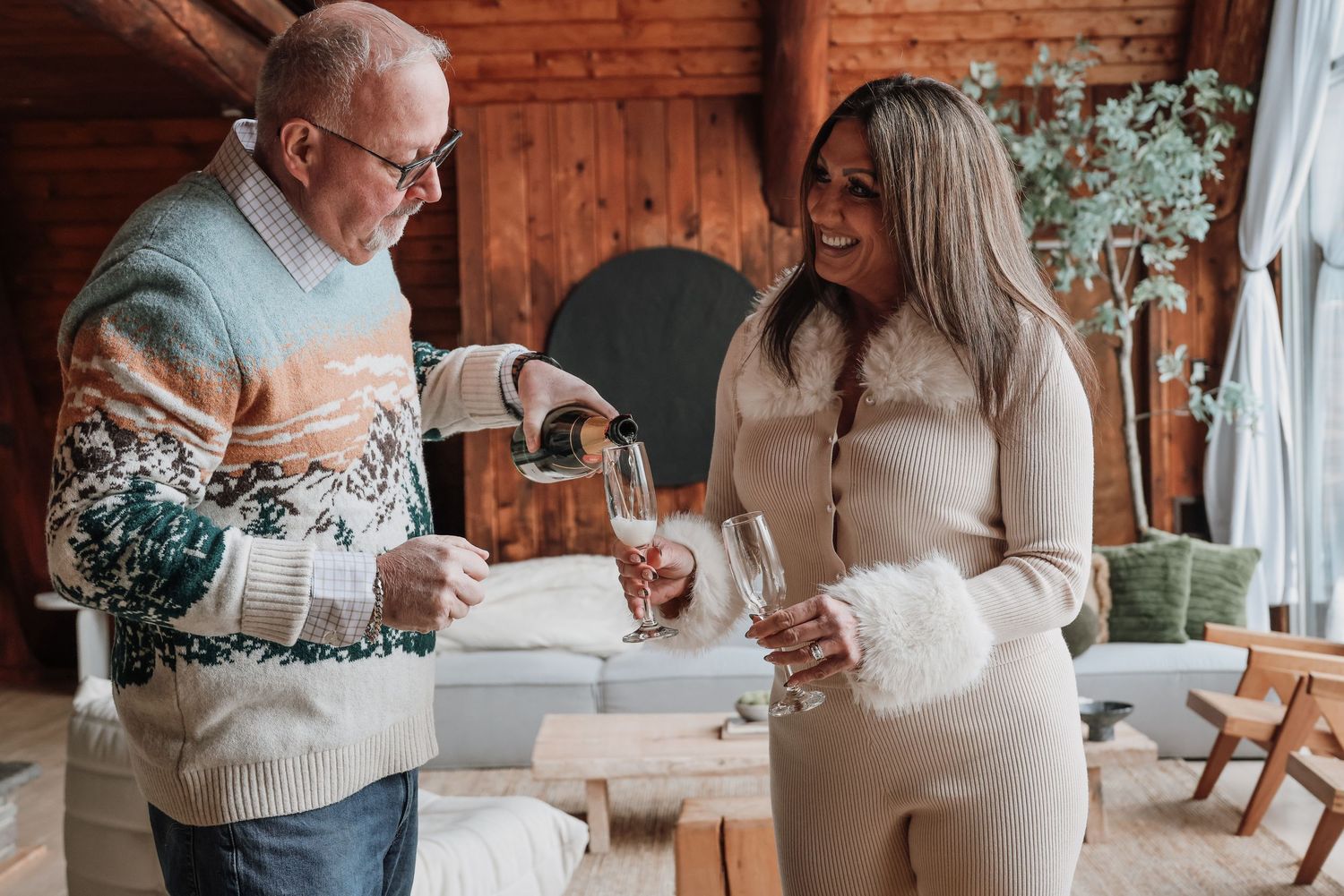 Cozy winter engagement photoshoot in rustic cabin with couple sharing hot cocoa and intimate moments.