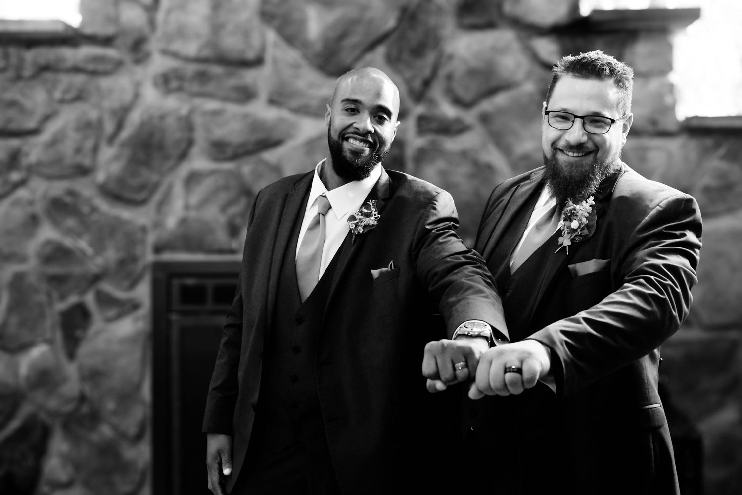 A black and white wedding photo collage showing groom details and candid moments against a stone wall backdrop.