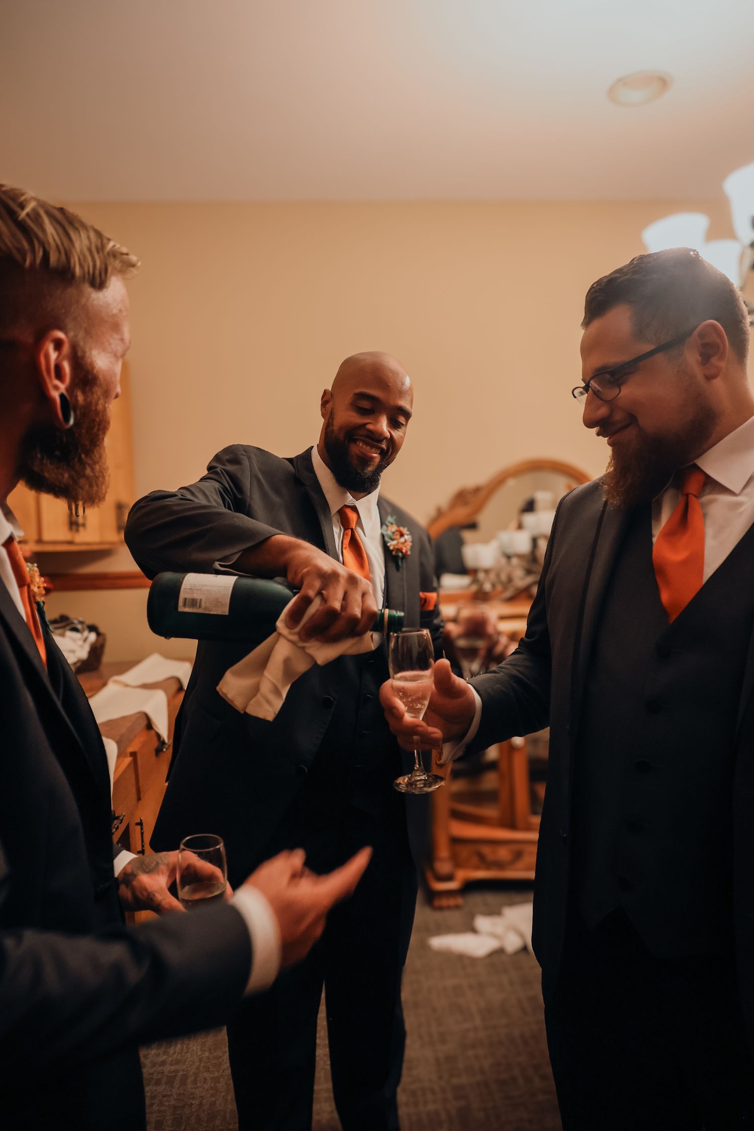 A group in formal black attire shares a celebratory toast with champagne glasses in an indoor setting.