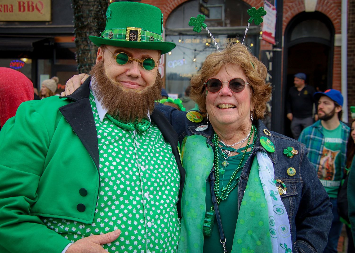People wearing green outfits and shamrock patterns celebrate St Patrick's Day at a festive gathering.