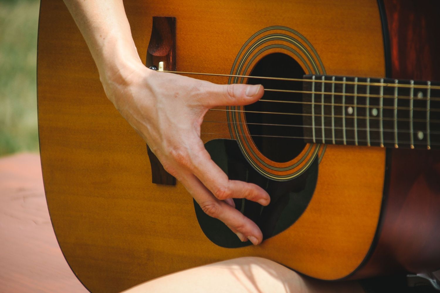Close-up view of hands playing an acoustic guitar showing strumming and fingerpicking techniques.