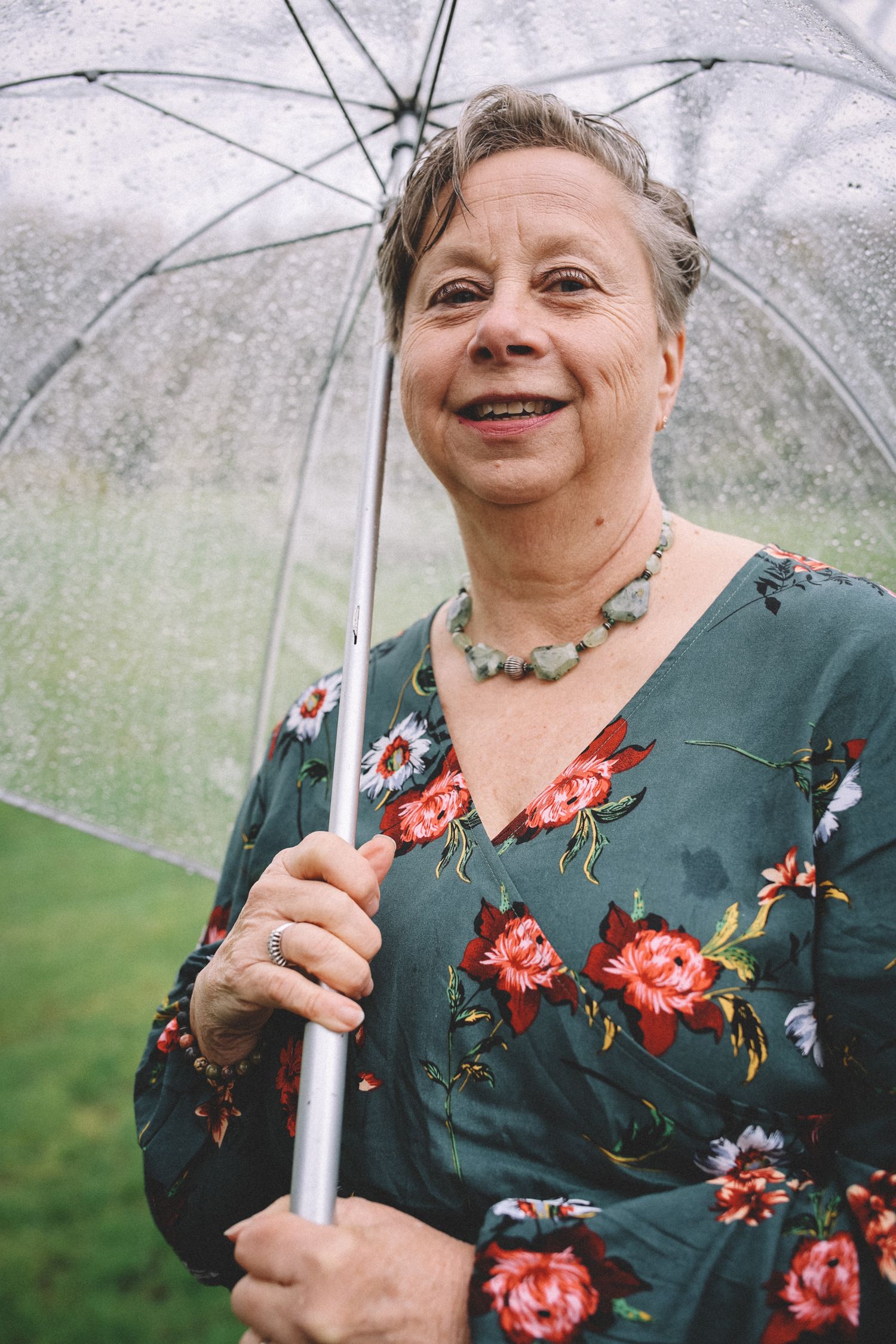 A series of photos showing someone in a green floral dress holding a clear umbrella on an overcast day.