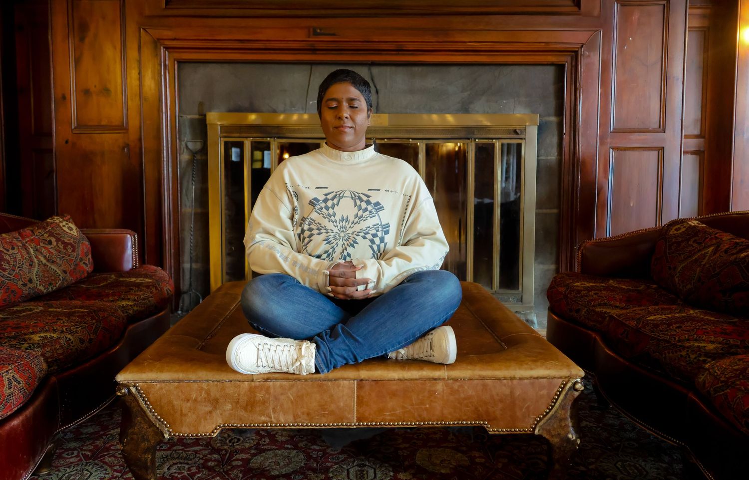 A panoramic sequence showing a person sitting on a brown leather couch in a wood-paneled room.