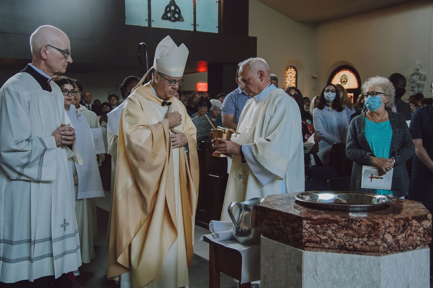 Religious clergy members gather around an altar during a ceremonial service in traditional robes.