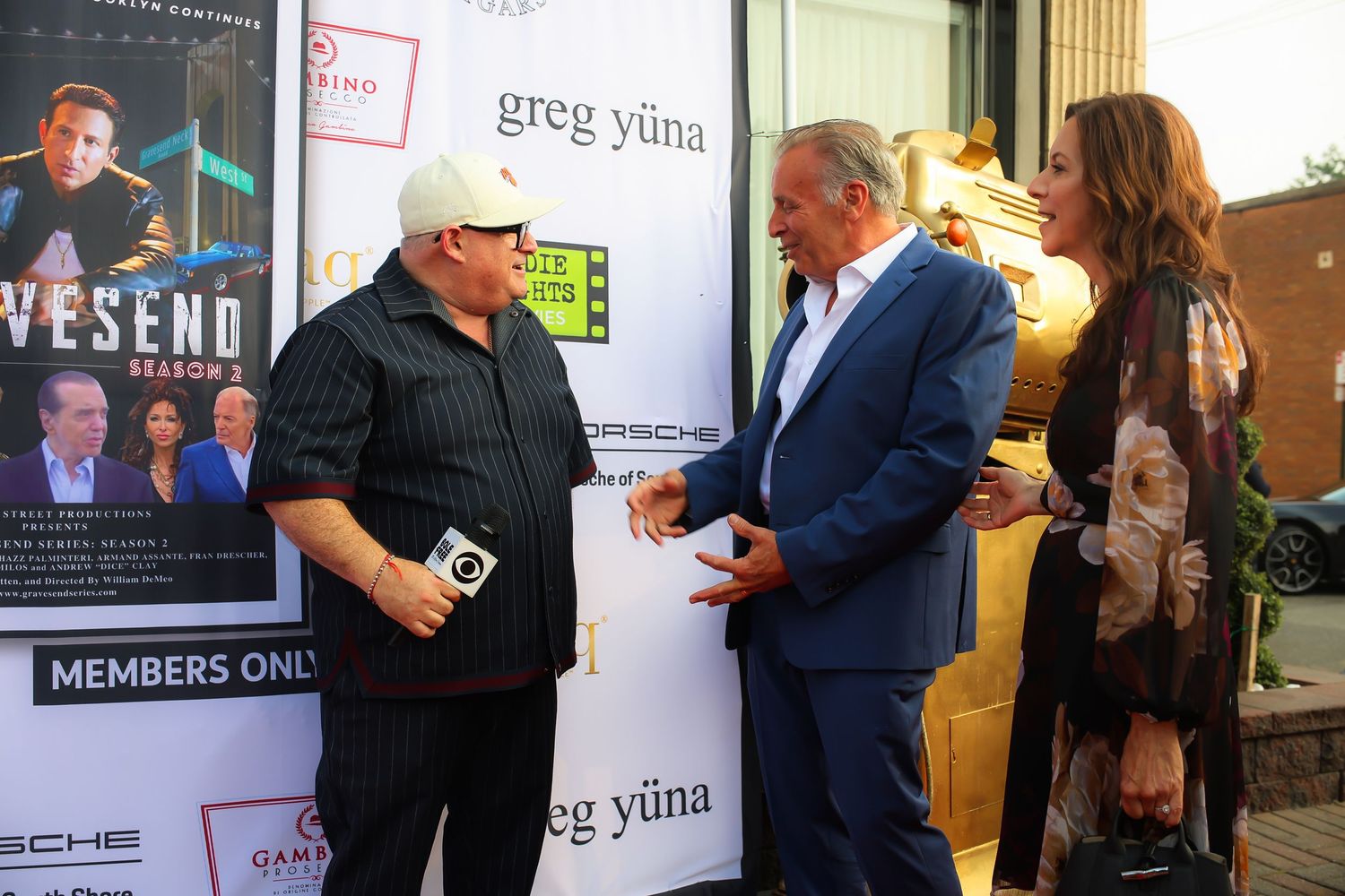 People interacting at a members-only event with promotional posters and signage visible in the background.