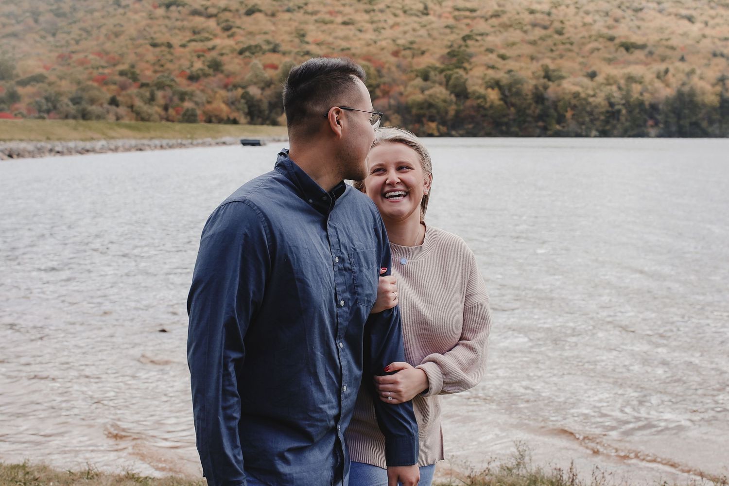 A couple embraces while standing in a desert landscape during golden hour.