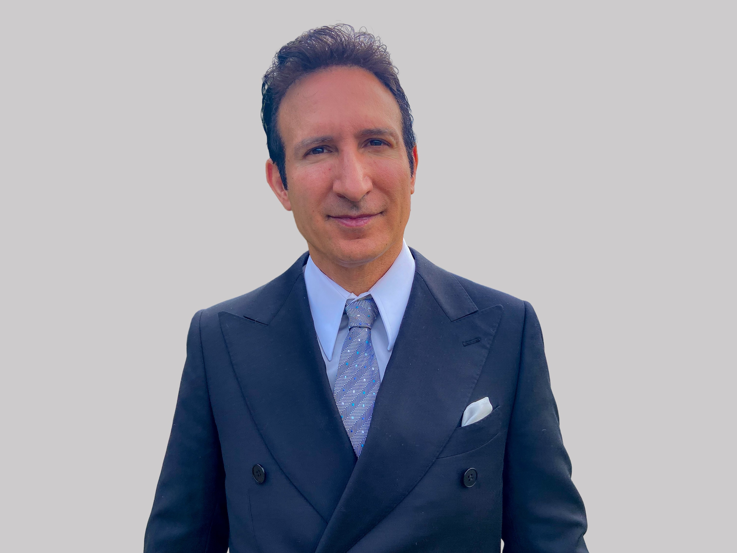 Professional in a navy suit and patterned tie poses in a series of four similar headshots against a light background.