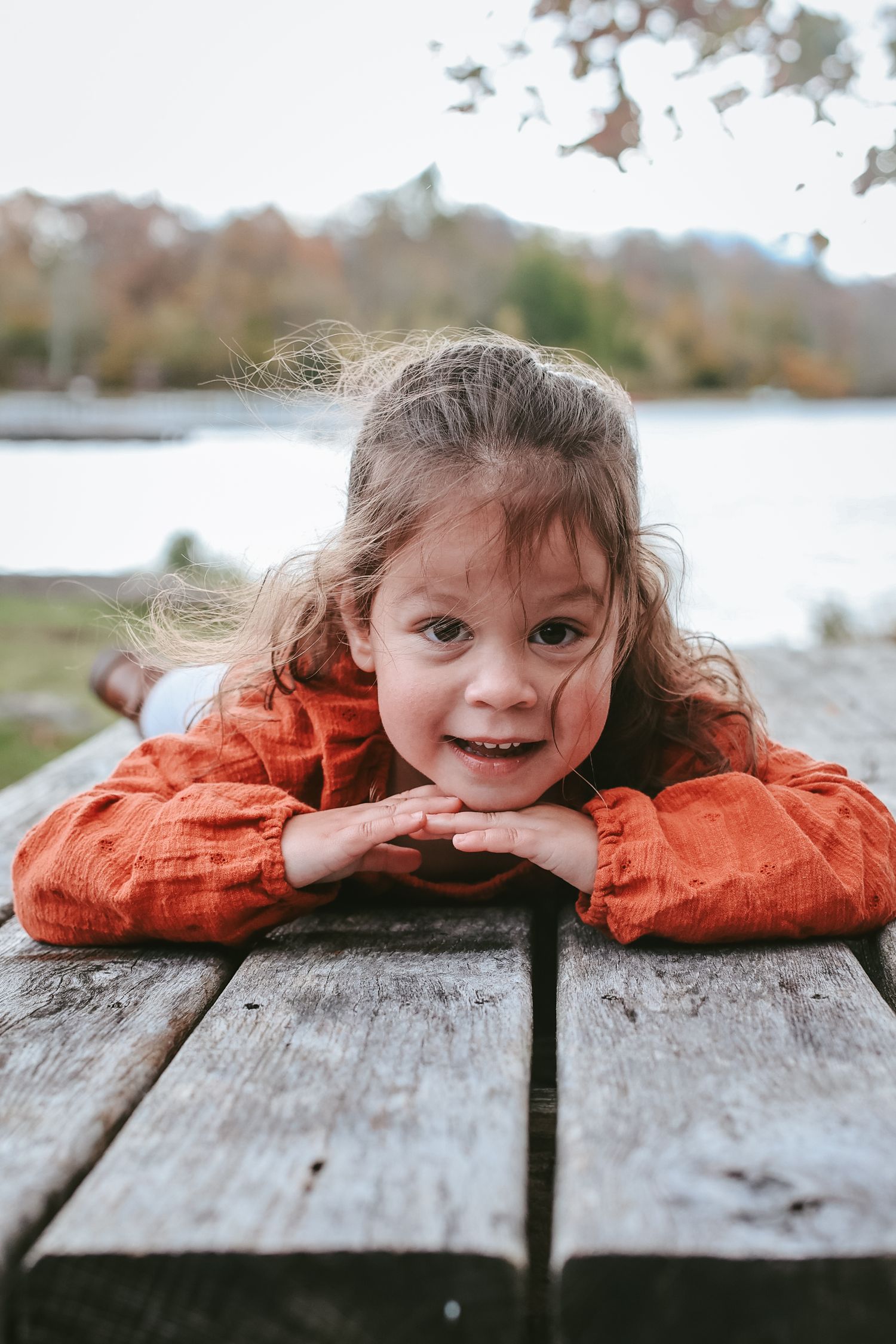 A series of playful photos shows someone peeking over a wooden deck or dock surface in an outdoor setting.