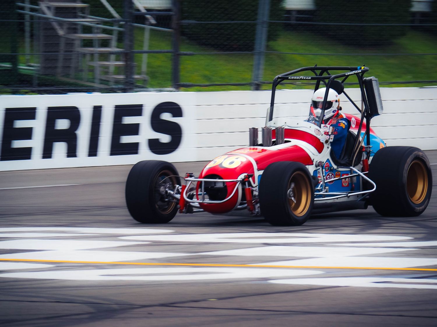 Racing cars speed around a wet racetrack during a competitive motorsport event.