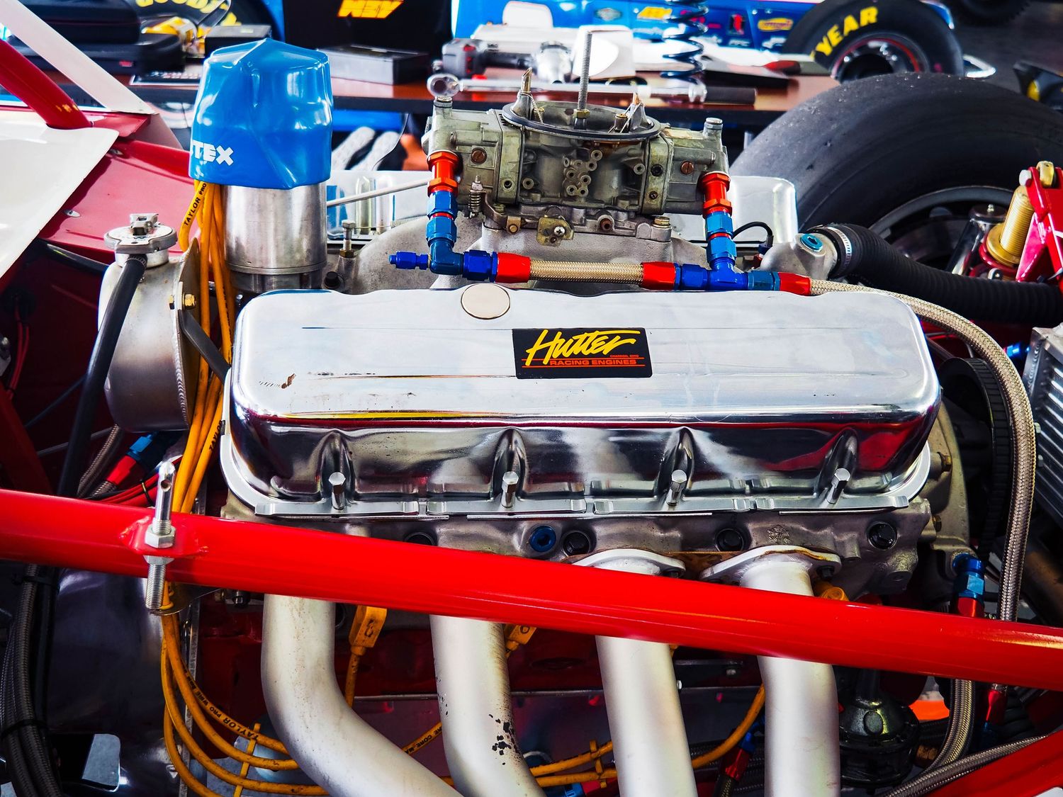 Close-up detail of a red and white racing car's rear wing and aerodynamic components at a motorsport event.